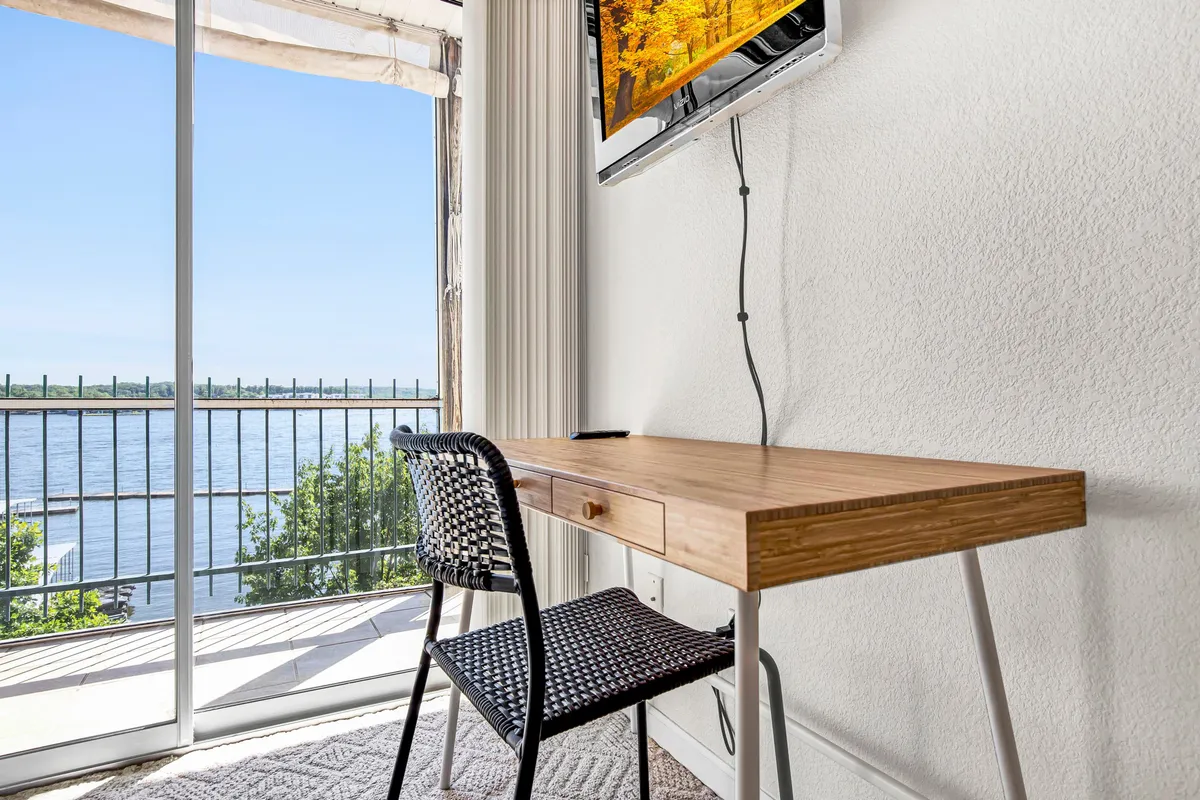A dedicated work area with a wooden desk and a black woven chair sits beside a large window, inviting both productivity and relaxation. The view outside the window reinforces the sense of serenity and connection to nature.