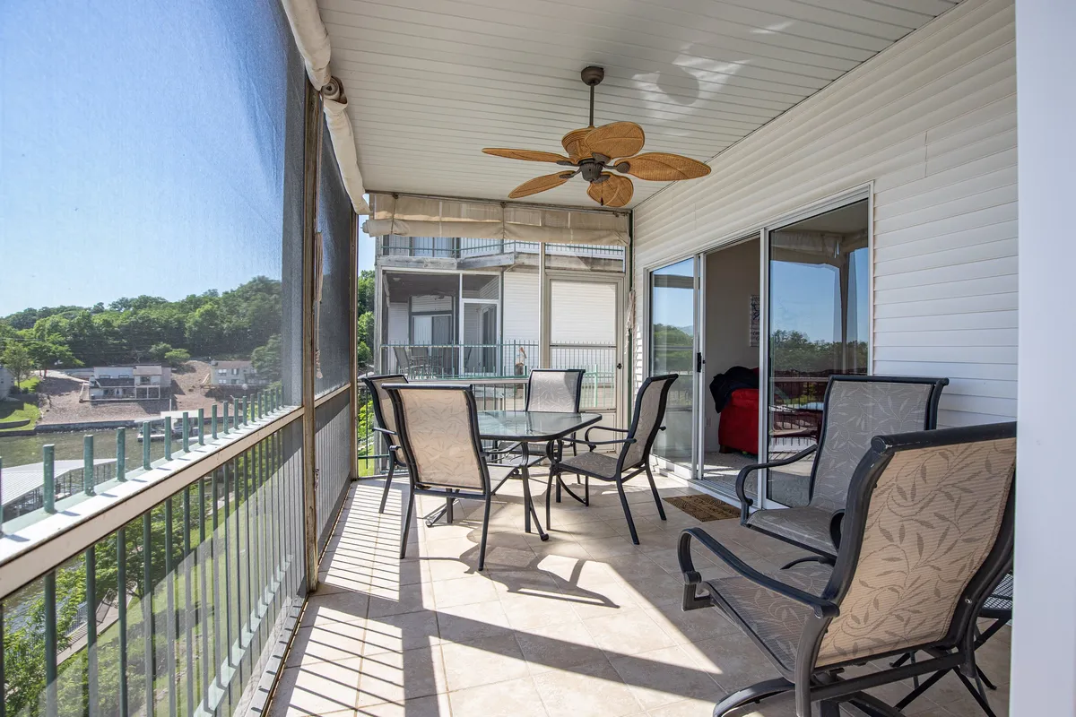 A peaceful exterior shot of an outdoor dining area with a table and ceiling fan, overlooking the surrounding landscape. The scene suggests a relaxing space for outdoor meals or unwinding after a day of adventure, capturing the breezy, social aspect of lakeside living.