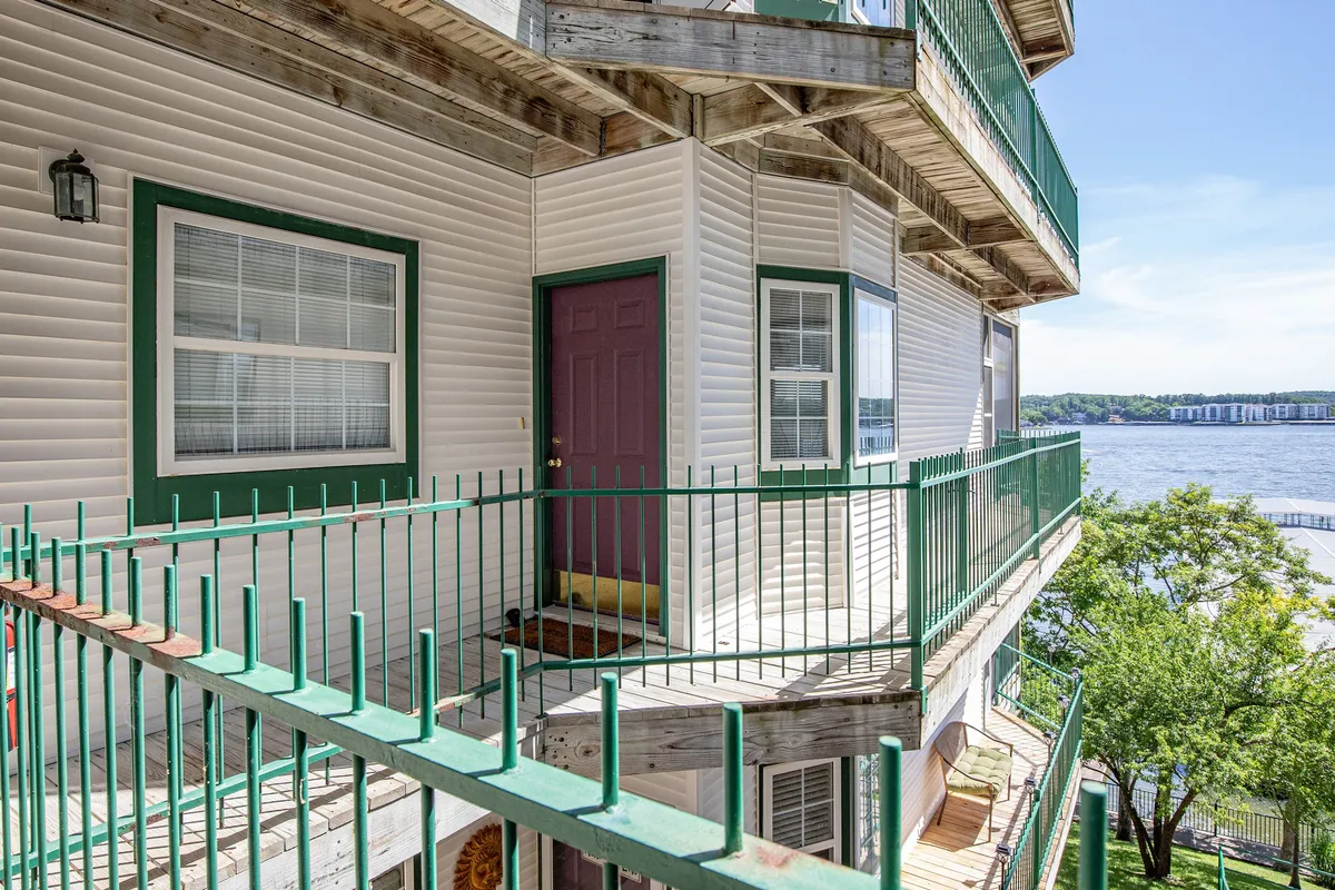 This image shows a private balcony with green railings and a burgundy door overlooking the expansive lake. The setup invites relaxation with ample space for seating, offering breathtaking and uninterrupted water views perfect for unwinding, sharing meals, or enjoying drinks as the sun rises or sets.