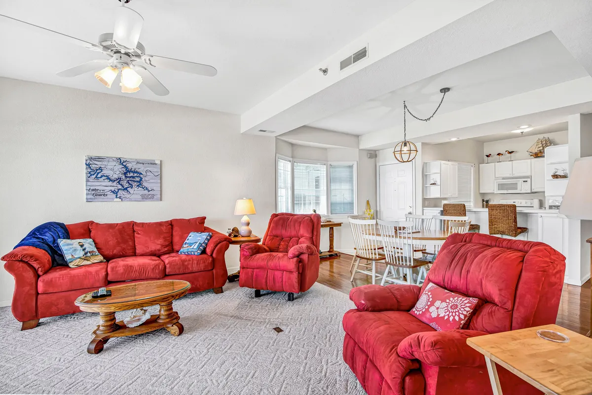 A cheerful living and dining area with plush red sofas, a wooden coffee table, a dining setup, and decorative wall art. The space is designed for both social gatherings and family relaxation, underscoring a homelike, bespoke atmosphere.