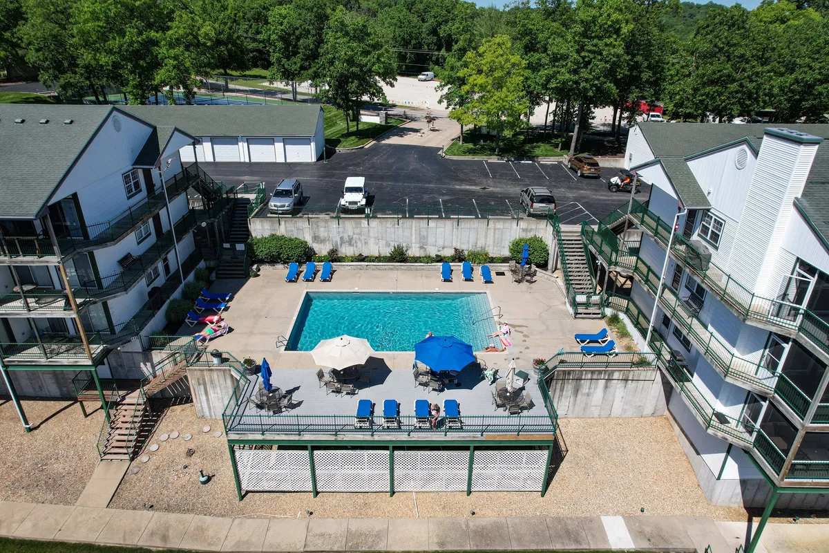 A second pool scene with lounge chairs, umbrellas, and lush greenery, offering a slightly different angle and vibe. The setting feels bright, open, and welcoming, emphasizing relaxation and social interaction by the water.