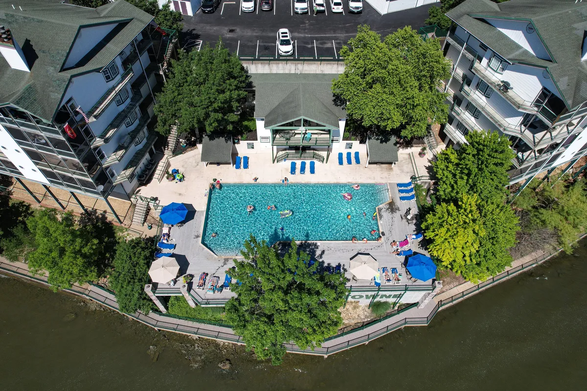A sparkling outdoor swimming pool surrounded by lounge chairs, umbrellas, and lush greenery, inviting guests to relax, sunbathe, and socialize by the water. The pool area exudes a cheerful, leisurely mood, perfect for daytime group fun.