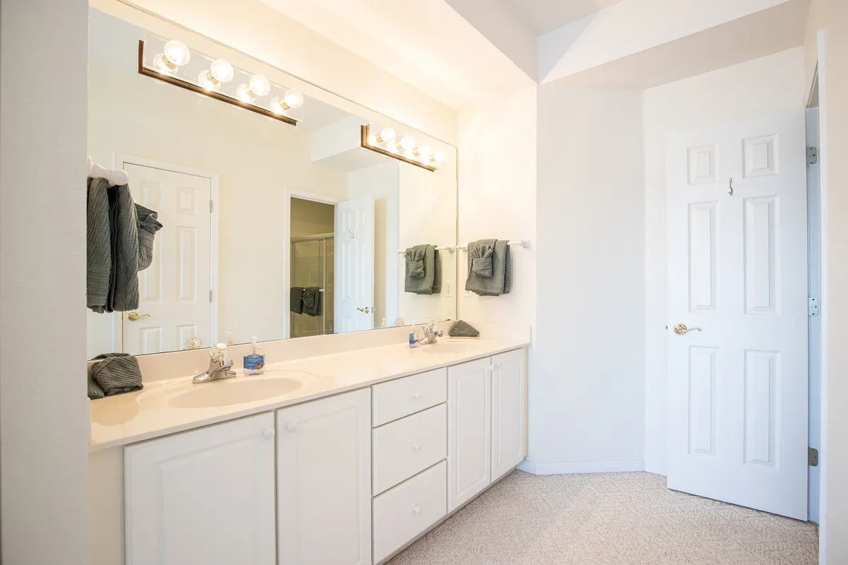 A spacious bathroom with a double vanity, large mirror, and elegant lighting fixtures creates an atmosphere of calm and organization—ideal for morning and evening self-care routines.
